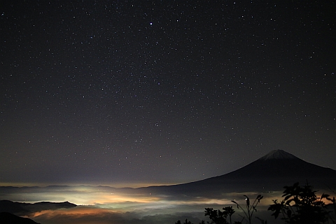 街並みの灯りに照らされる雲と、富士山と、満点の星空